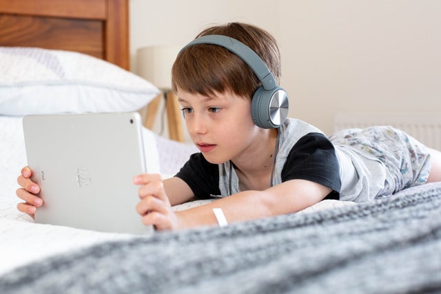 Young boy watching a tablet while wearing headphones during screentime