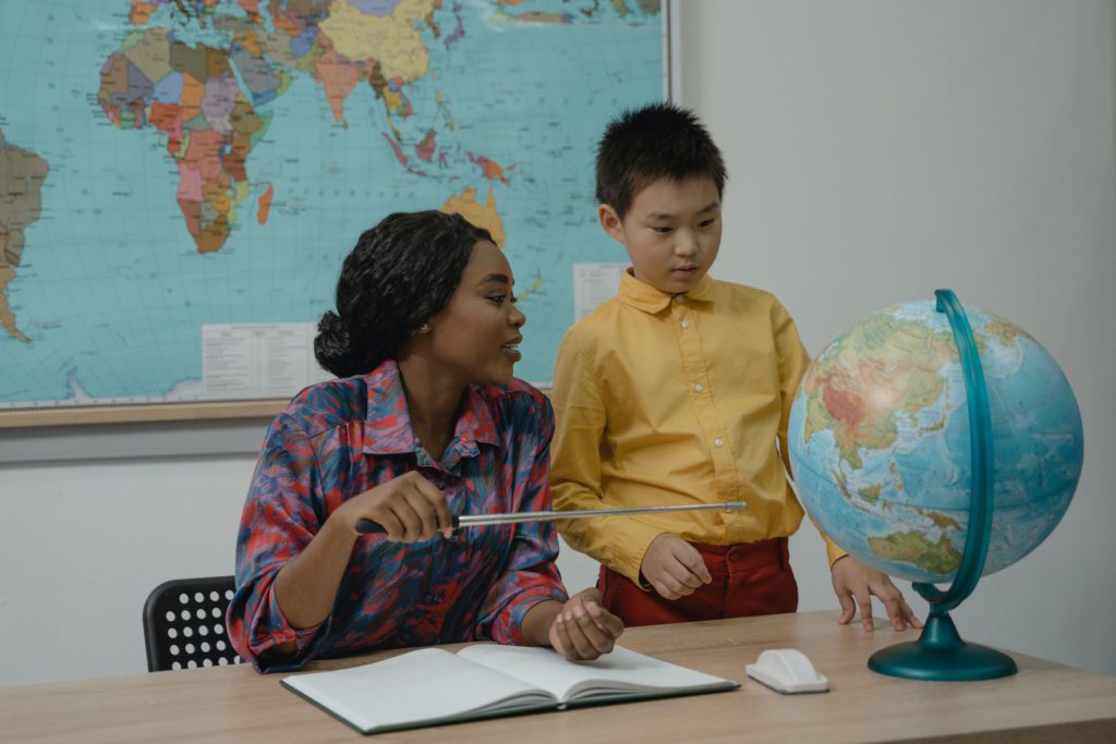 Teacher and student in classroom looking at a globe