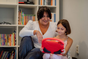 Woman and young girl looking at a tablet together. If you're wondering why your kid loves Roblox, check out our Roblox Parent Guide for the inside scoop.