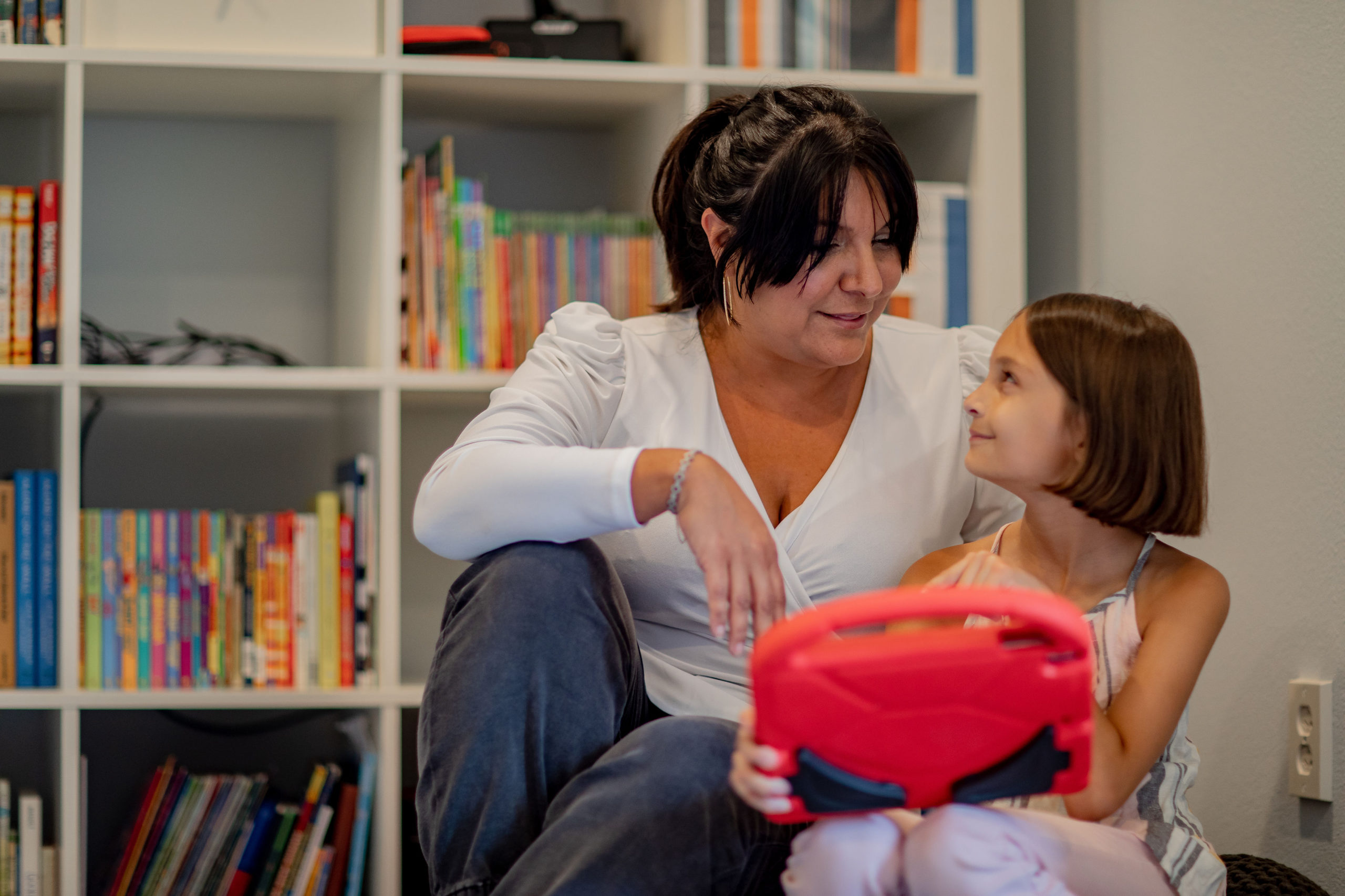 A grandmother and young girl are looking at a tablet. When she plays Roblox with Kinjo, they can both track her Cognitive Challenge Score and bring more learning to her game time.