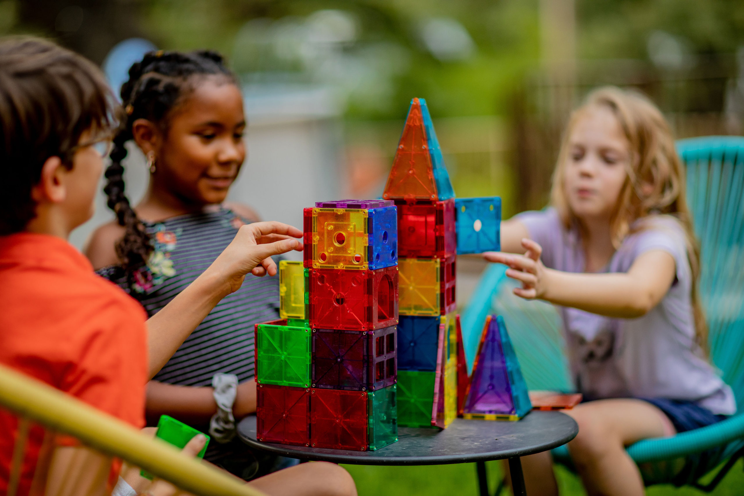 3 kids playing with magnetic tiles, enjoying the benefits of play-based learning.