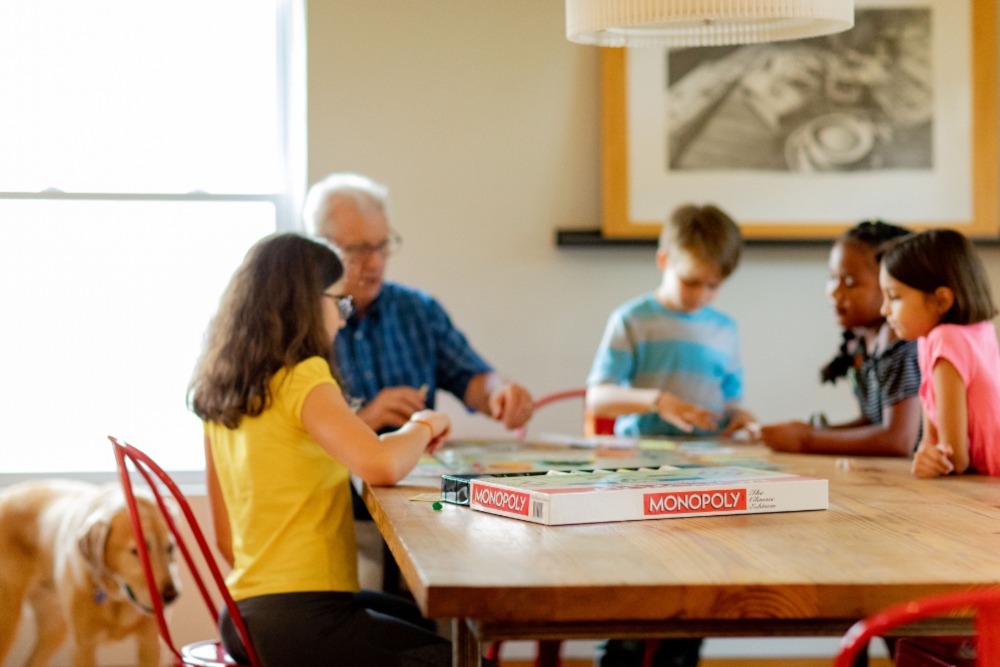 Kids and grand parent are playing a board game together.