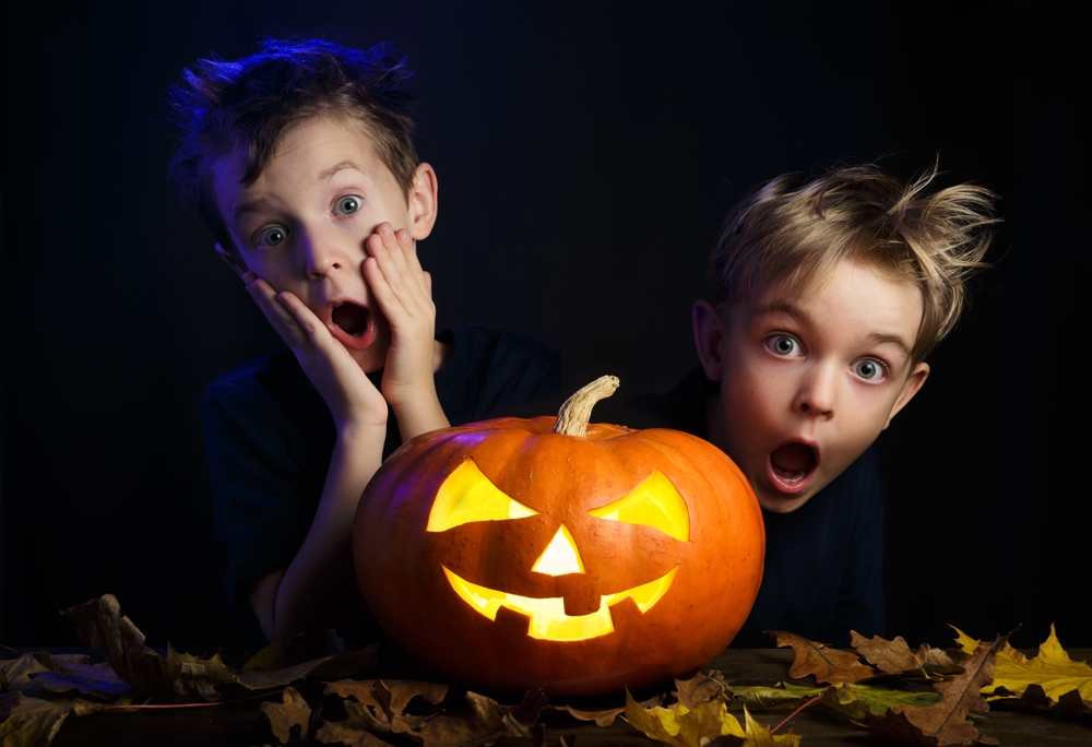 2 young boys with surprised faces standing behind a jack o lantern. Are you surprised to discover these benefits of video games?